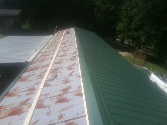 Old rusted panels beside newly installed green metal roofing — Wind Damage Roof Repair by Roofing Brothers in North Wales