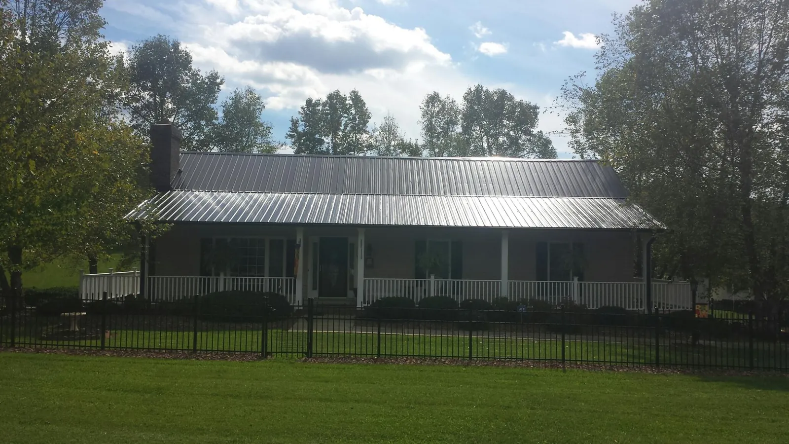 Gray metal roof on a brick ranch with a full width front porch — Gutter Guard Installation work by our crew in North Wales