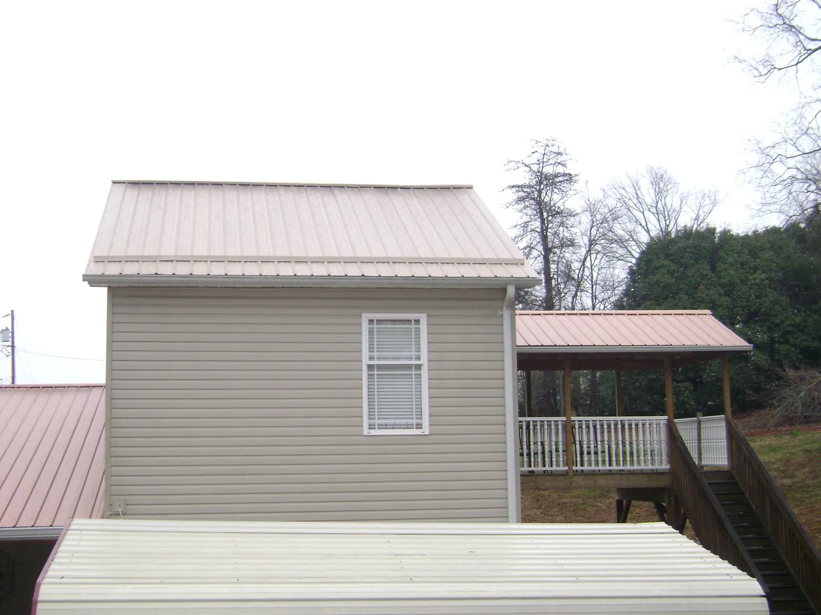 Tan metal roofs on a two story addition and attached porch, from a Roof Replacement job in North Wales