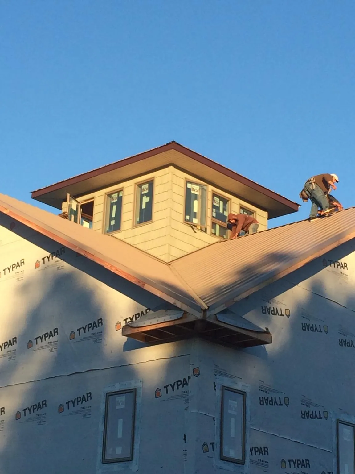 Roofers working around a rooftop cupola on a new metal roof at sunset — Roof Waterproofing in North Wales by Roofing Brothers